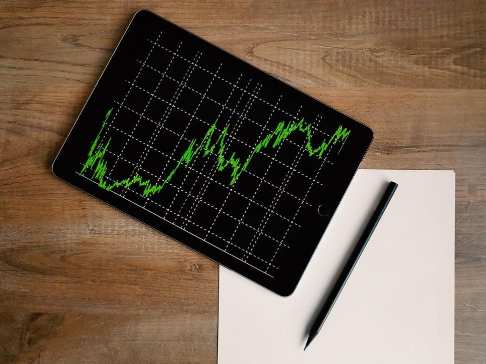 Free Image of Tablet with stock market analysis next to paper 