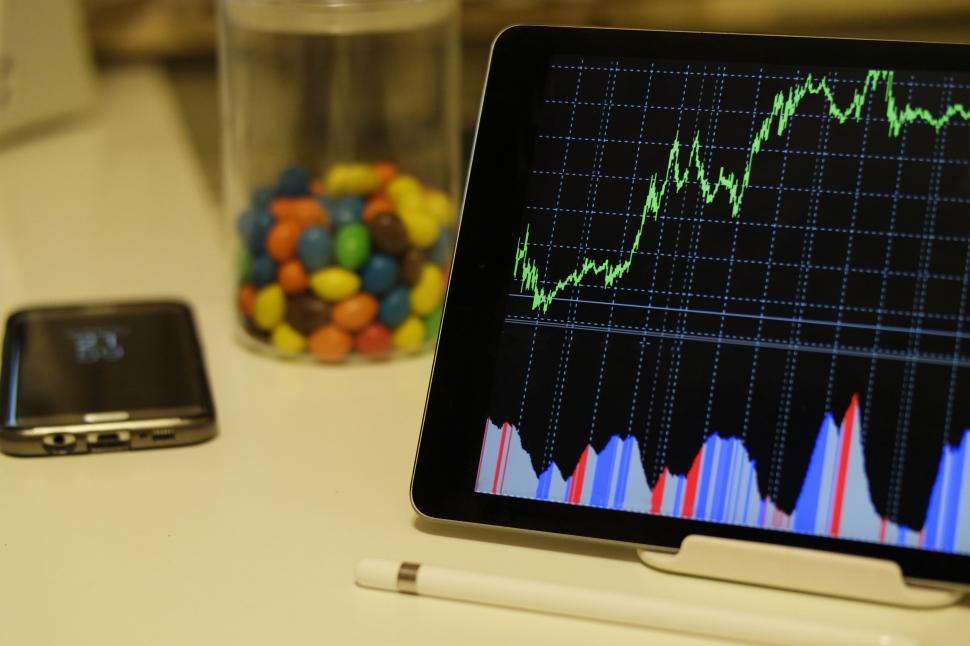 Free Image of Tablet displaying stock market data next to candy 