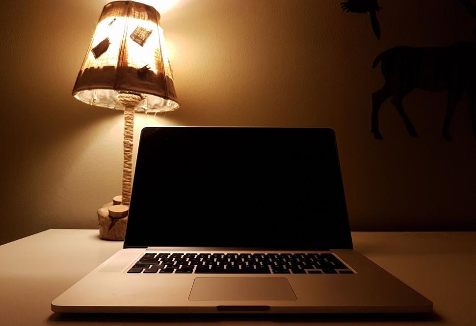 Free Image of Laptop with warm lamp glow on desk at night 