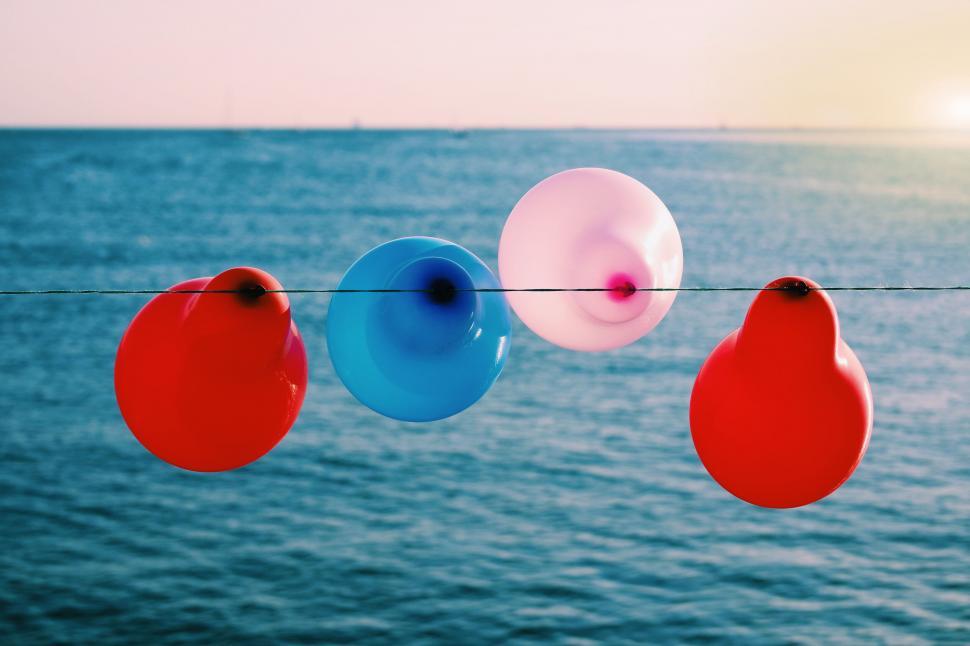 Free Image of Colorful balloons floating by the sea at sunset 