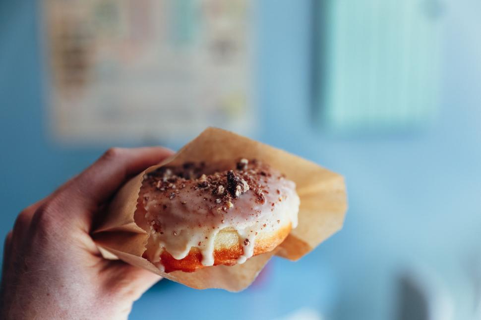 Free Image of Hand holding a dripping glazed donut 