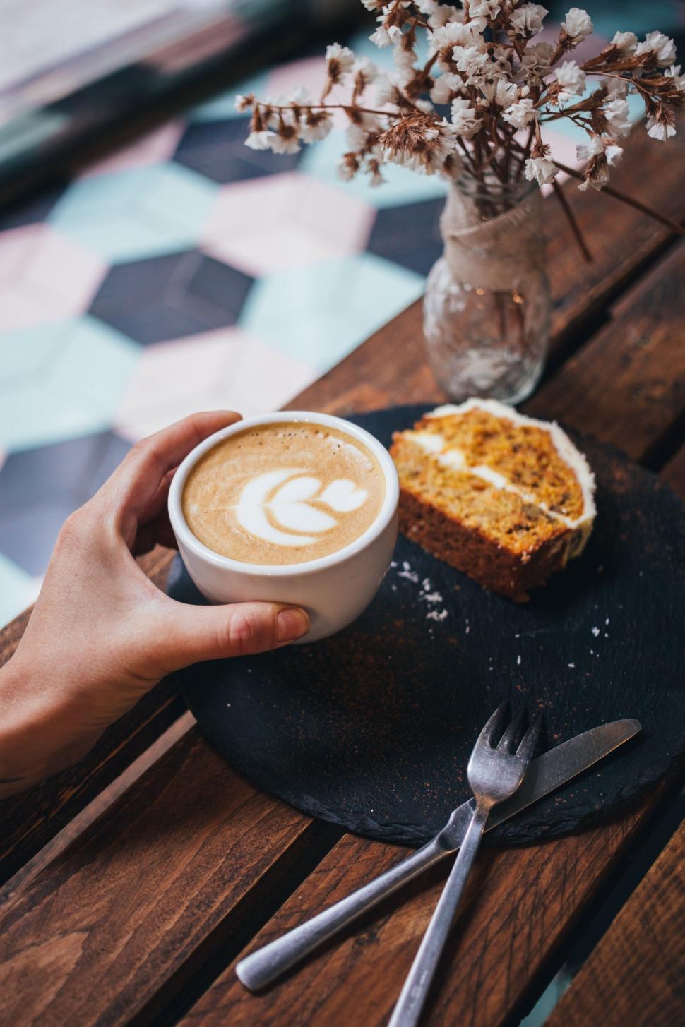 Free Image of Person holding a cup of coffee with cake 