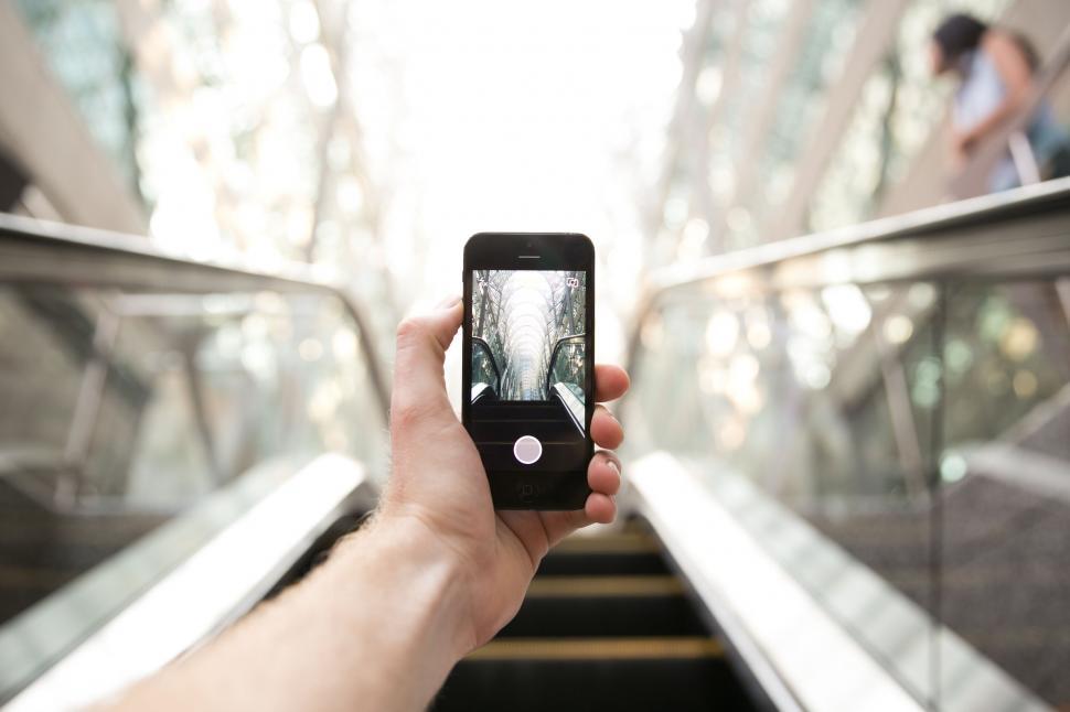 Free Image of Smartphone capturing cityscape on escalator 