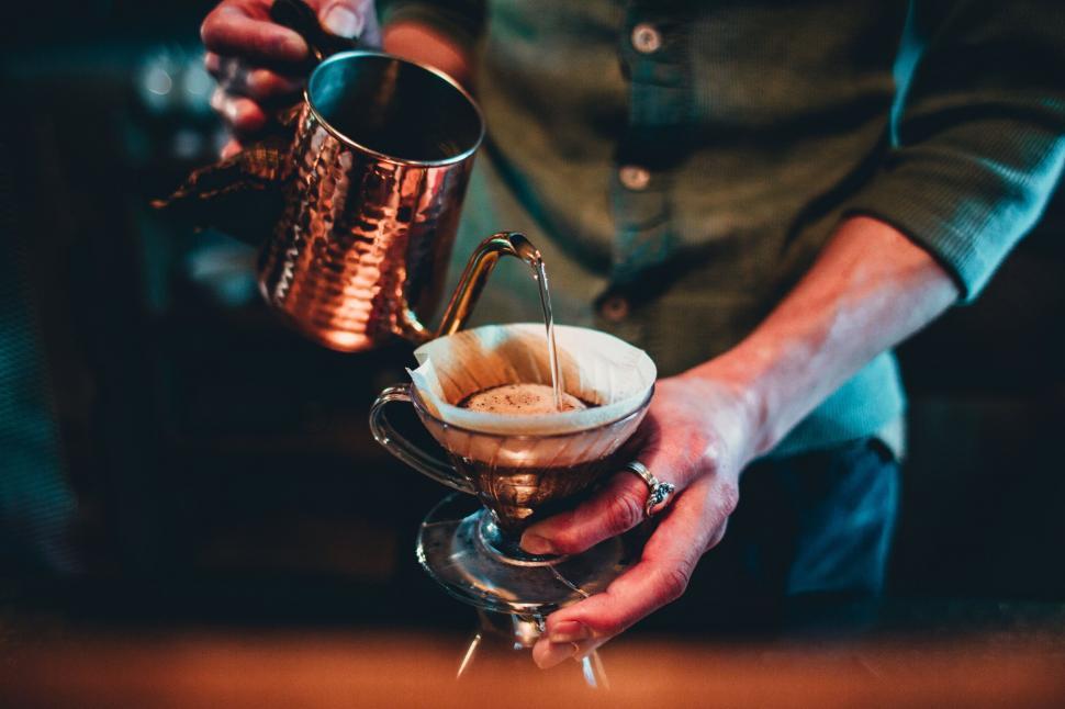 Free Image of Person pouring coffee with a brass pot 