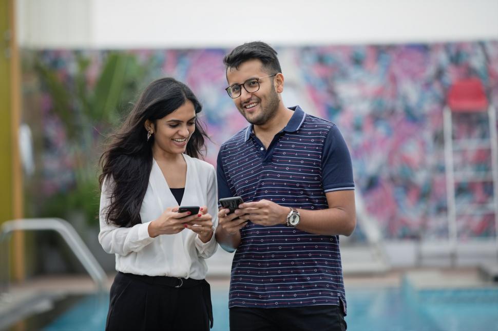 Free Image of Two people smiling using smartphones 