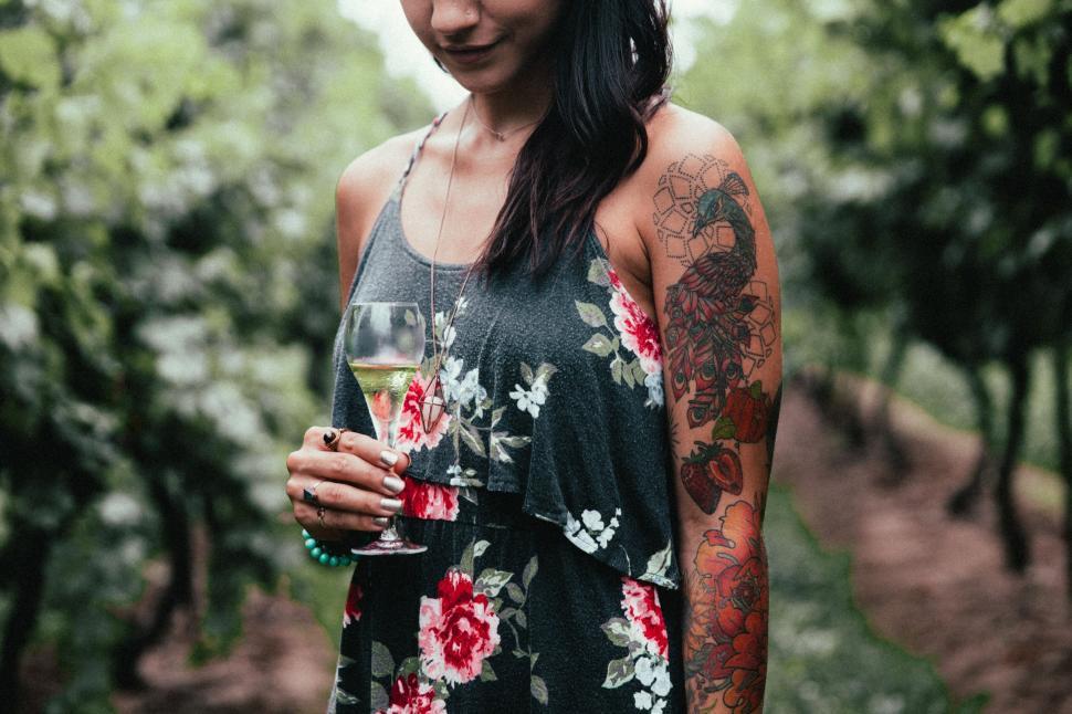 Free Image of Woman with tattoos holding a glass of wine 