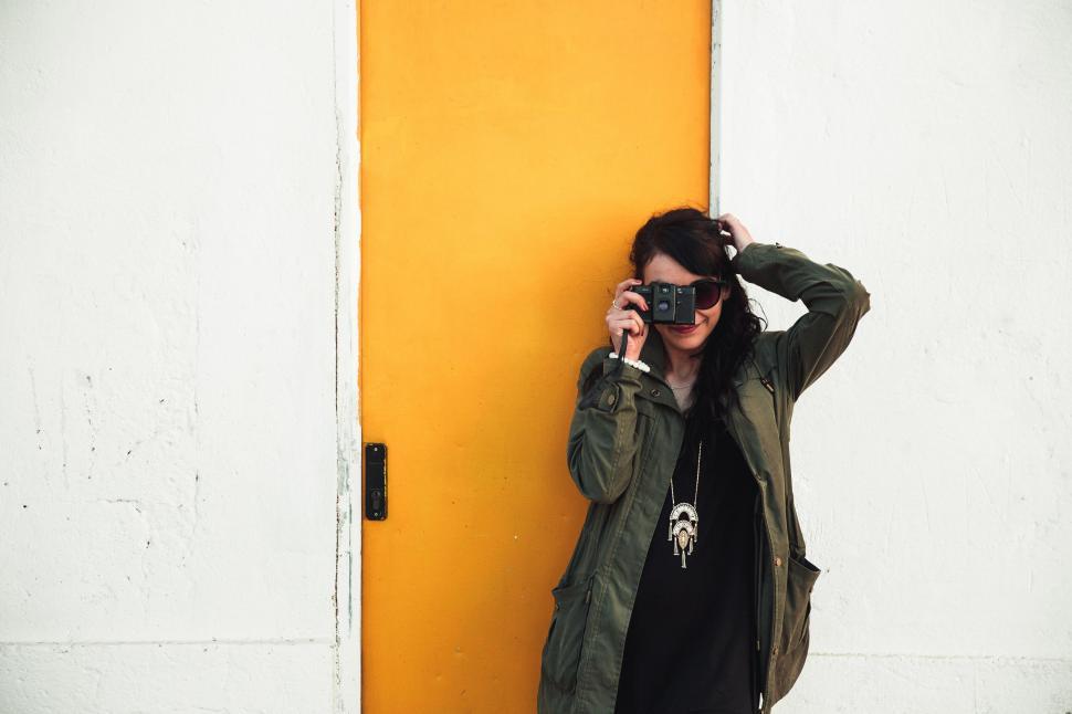 Free Image of Woman posing against yellow door and wall 