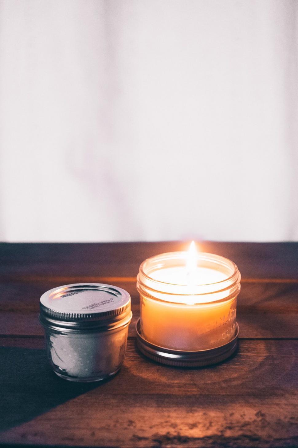 Free Image of Lit candle in a jar on a wooden table 