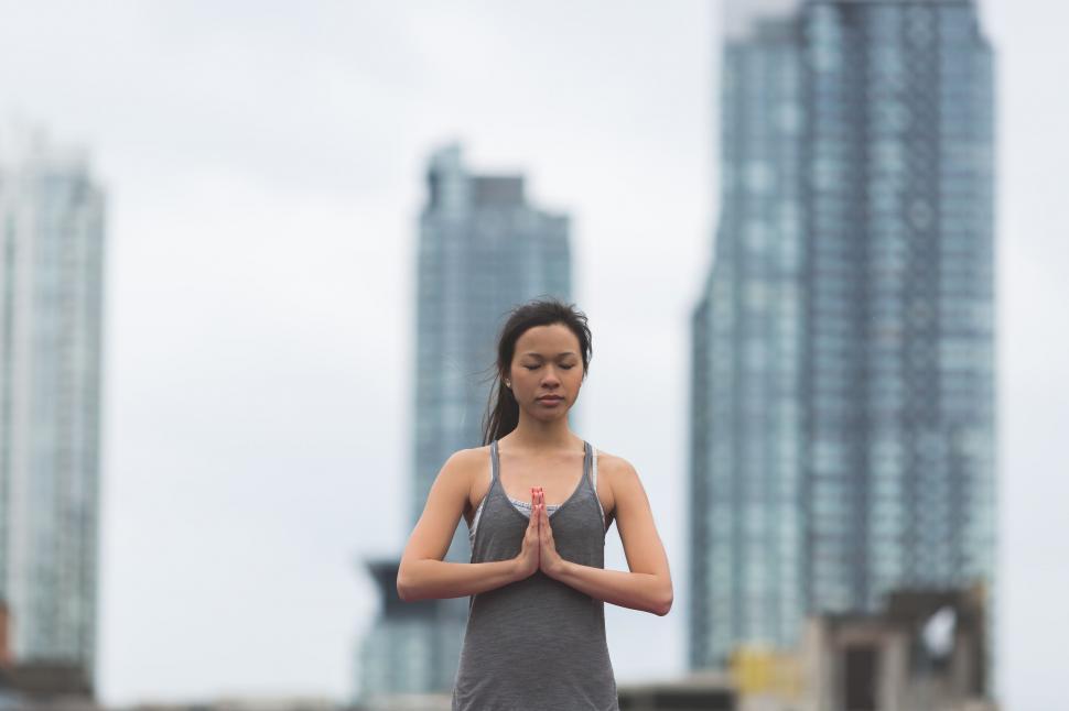 Free Image of Woman meditating with city backdrop 