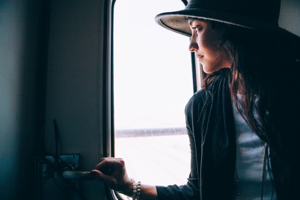 Free Image of Woman gazing out of train window wearing hat 