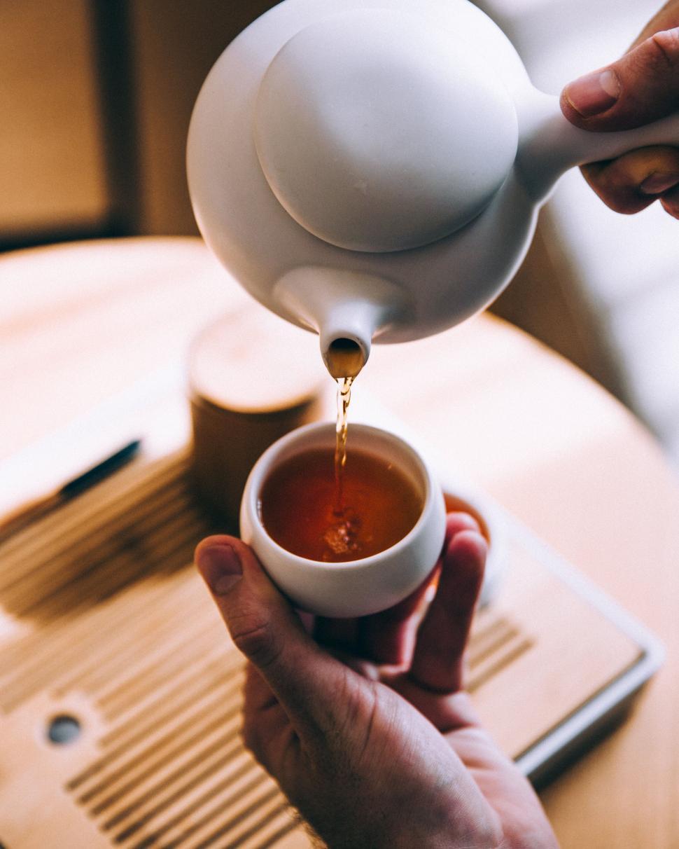 Free Image of Pouring tea into a cup in a wooden setting 