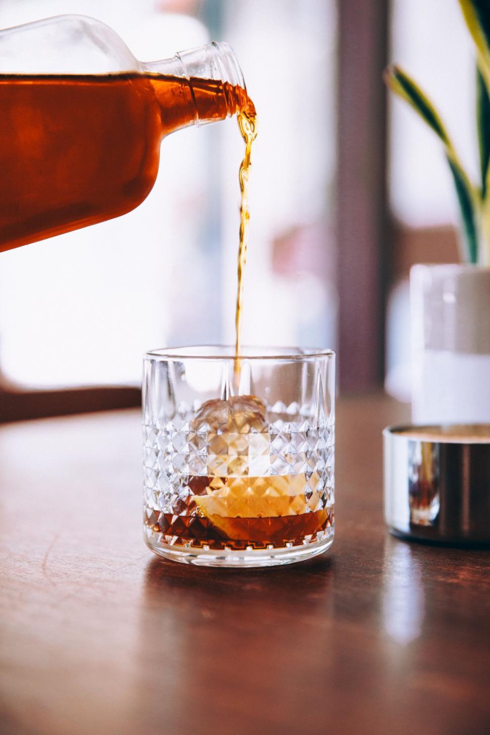 Free Image of Pouring whiskey into a glass with ice cubes 