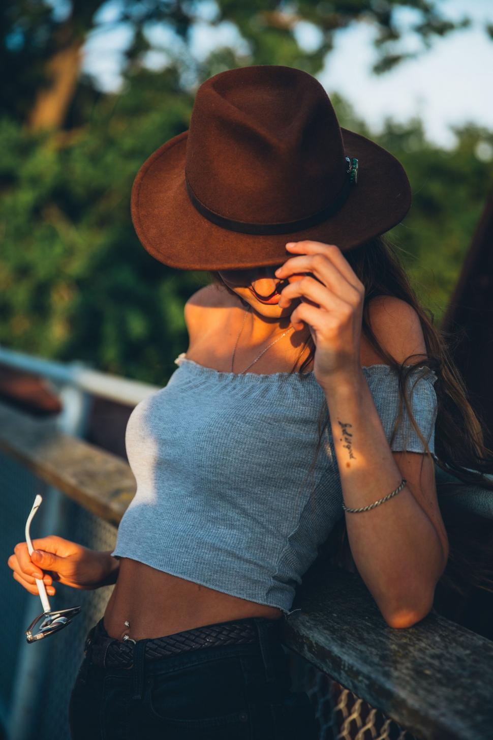 Free Image of Fashionable woman adjusting hat with sunglasses 