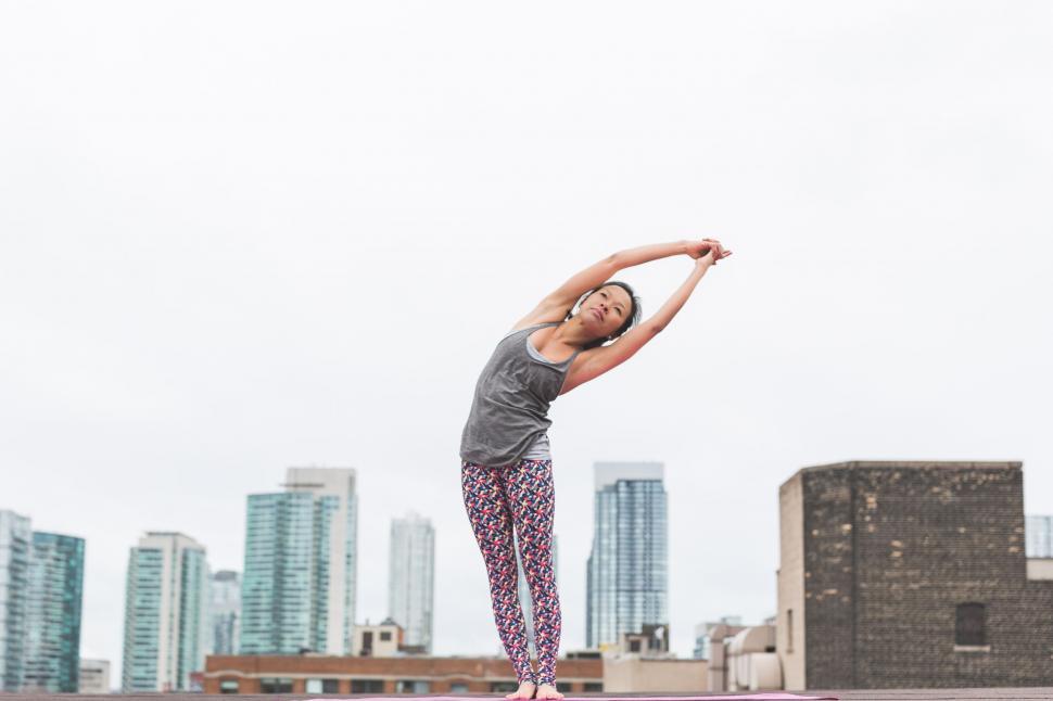 Free Image of Woman doing yoga with a city skyline view 