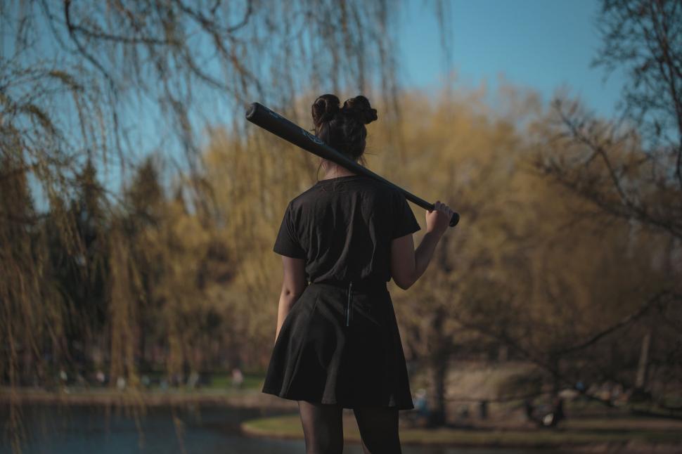 Free Image of Woman carrying baseball bat in serene park 