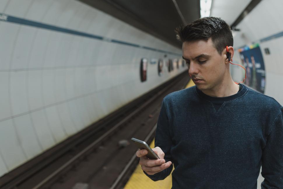 Free Image of Man on subway platform using phone 
