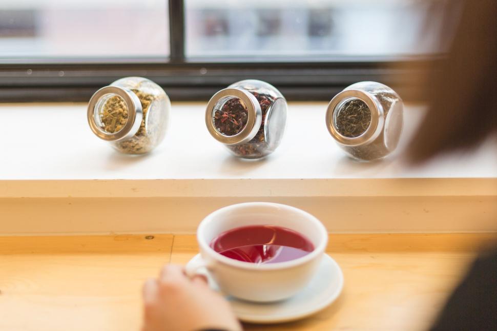 Free Image of Cup of tea in focus with jars blurred 