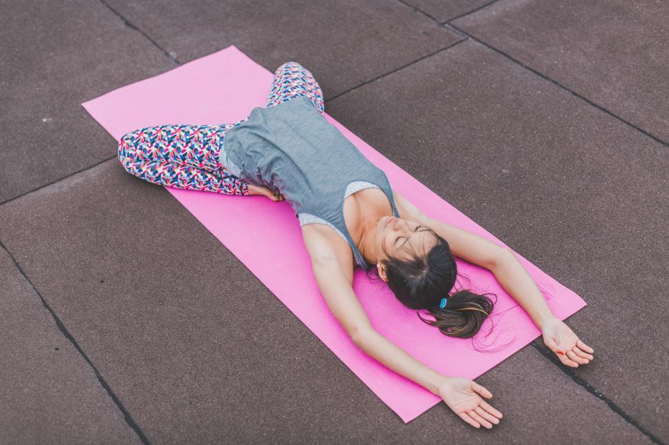 Free Image of Woman relaxing after workout on pink mat 