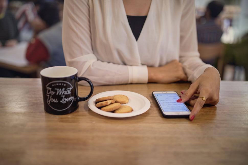 Free Image of Woman using smartphone with coffee and cookies 