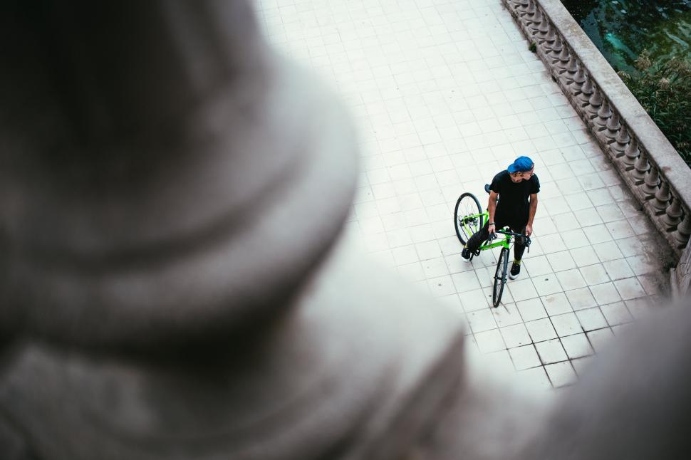Free Image of Cyclist resting with bike in urban plaza 