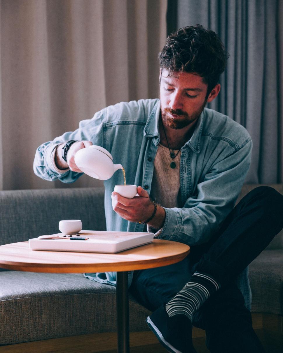 Free Image of Man pouring tea in a relaxed setting 