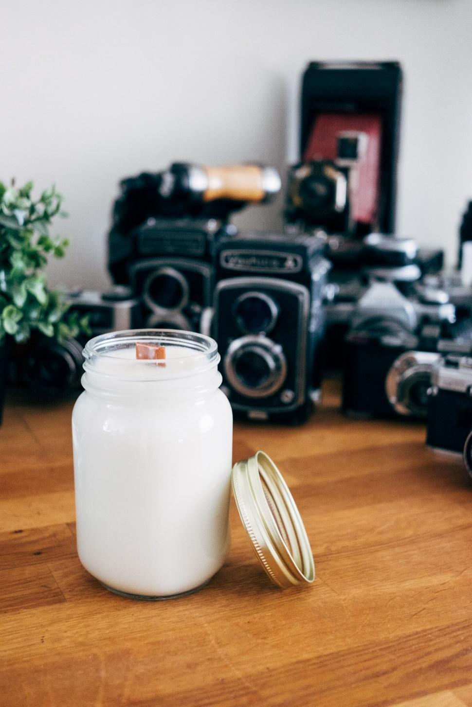 Free Image of Vintage cameras around a white candle jar 
