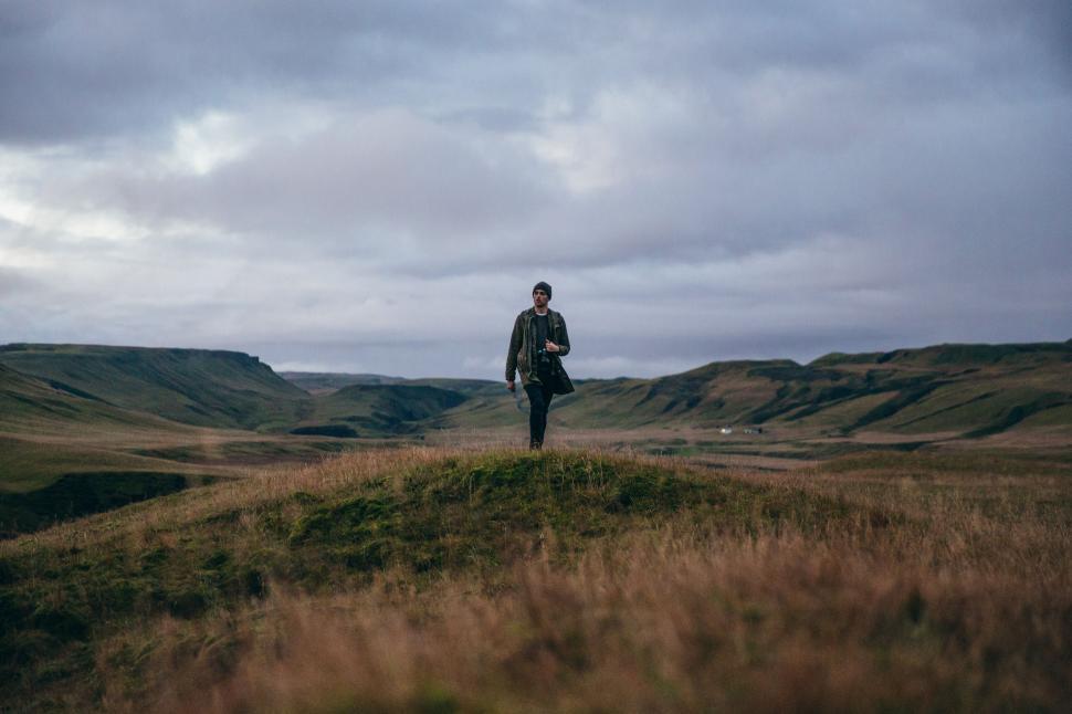 Free Image of Man walking alone in vast grassy landscape 