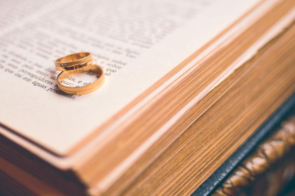 Free Image of Golden wedding rings on a vintage book s page 