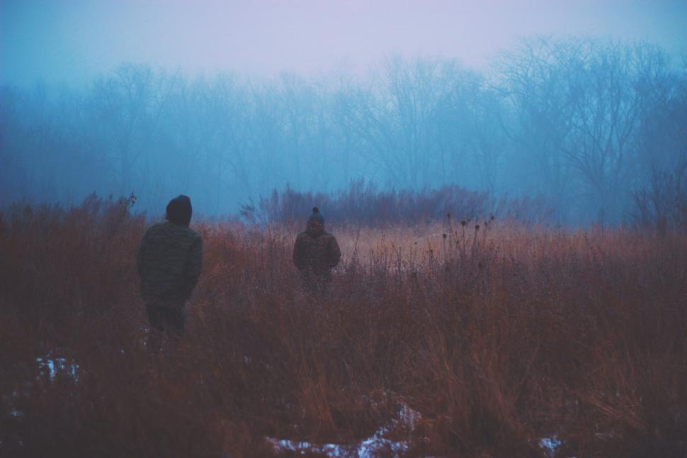 Free Image of Two hunters trek through snowy wilderness 