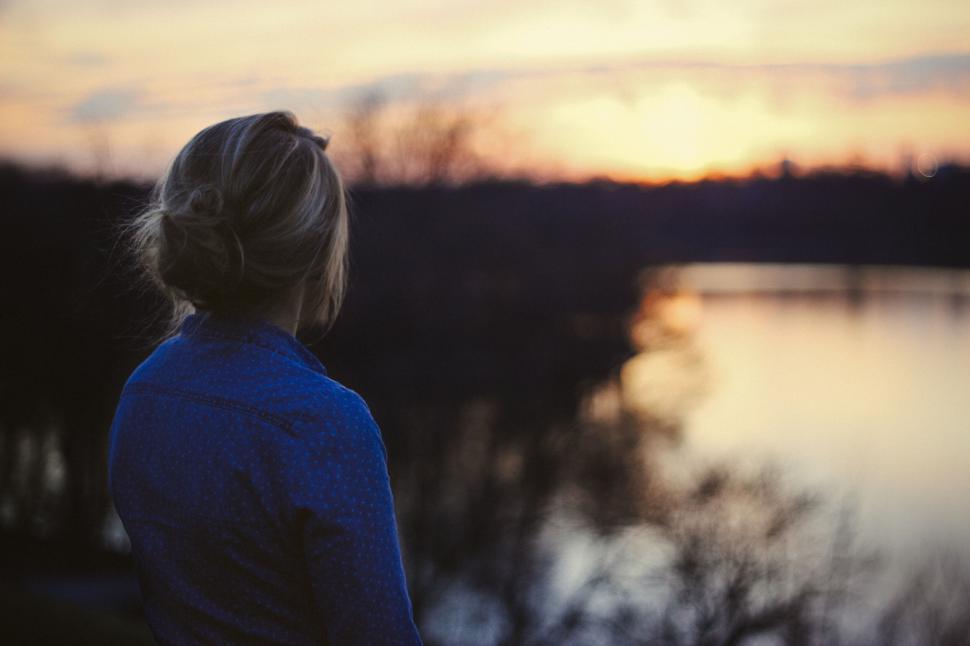 Free Image of Woman gazing sunset over tranquil lake 