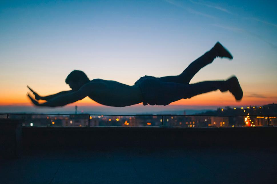 Free Image of Man silhouetted against sunset performing plank 