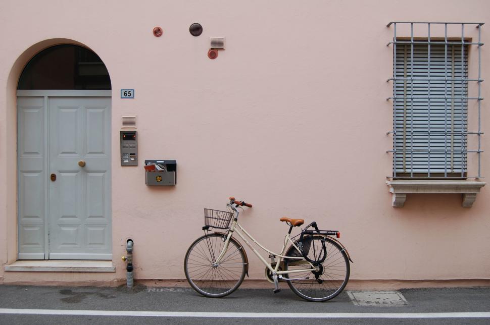 Free Image of Bicycle parked against pink wall with door 