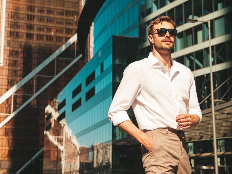 Free Image of A man in sunglasses standing in front of a building 
