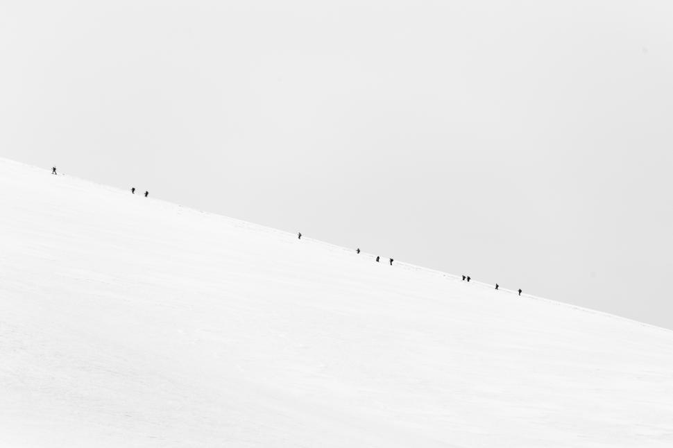 Free Image of A group of people walking up a snowy hill 