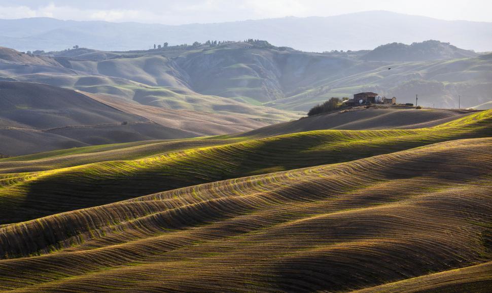 Free Image of A rolling hills with a house in the distance 