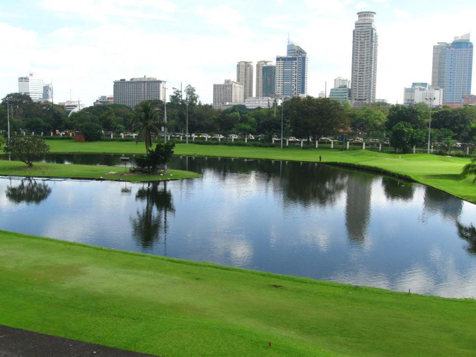 Free Image of Golf Course With Pond and City in Background 