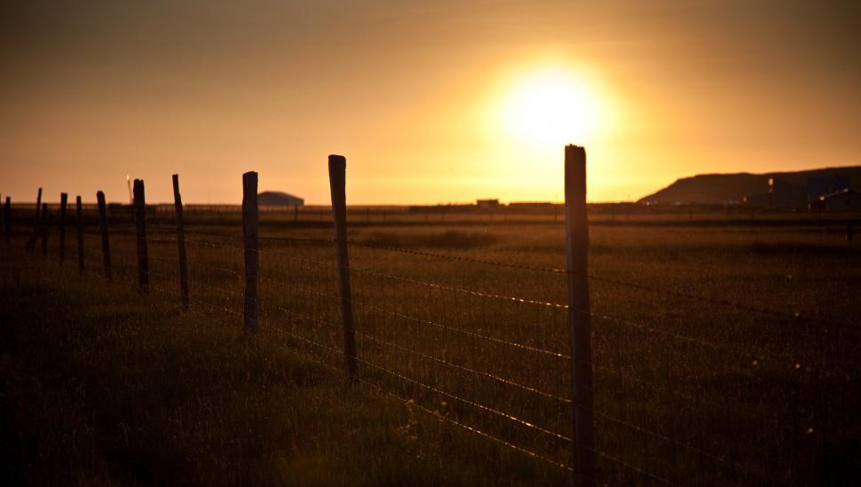 Free Image of A fence in a field with a sunset 