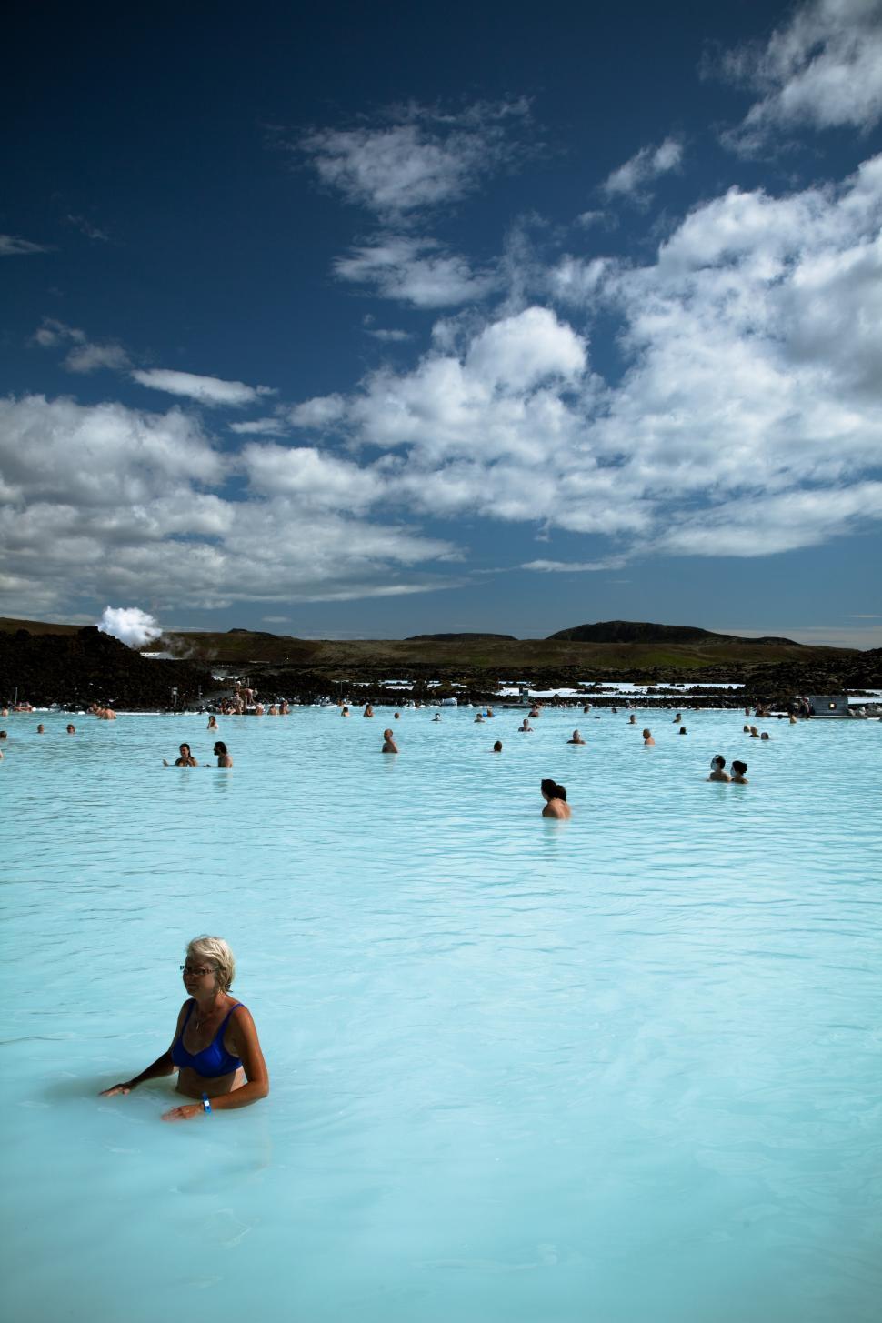 Free Image of A group of people in a blue pool with blue lagoon in the background 