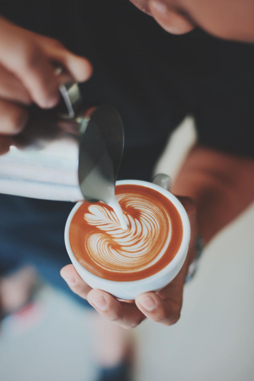 Free Image of Barista creating latte art in coffee cup 