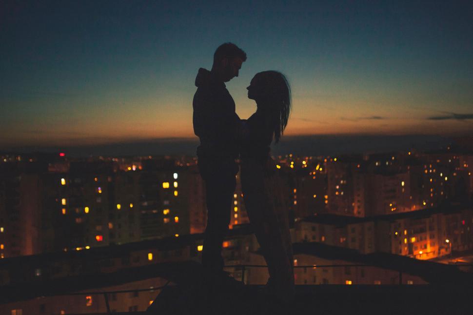 Free Image of Couple silhouetted against cityscape at dusk 