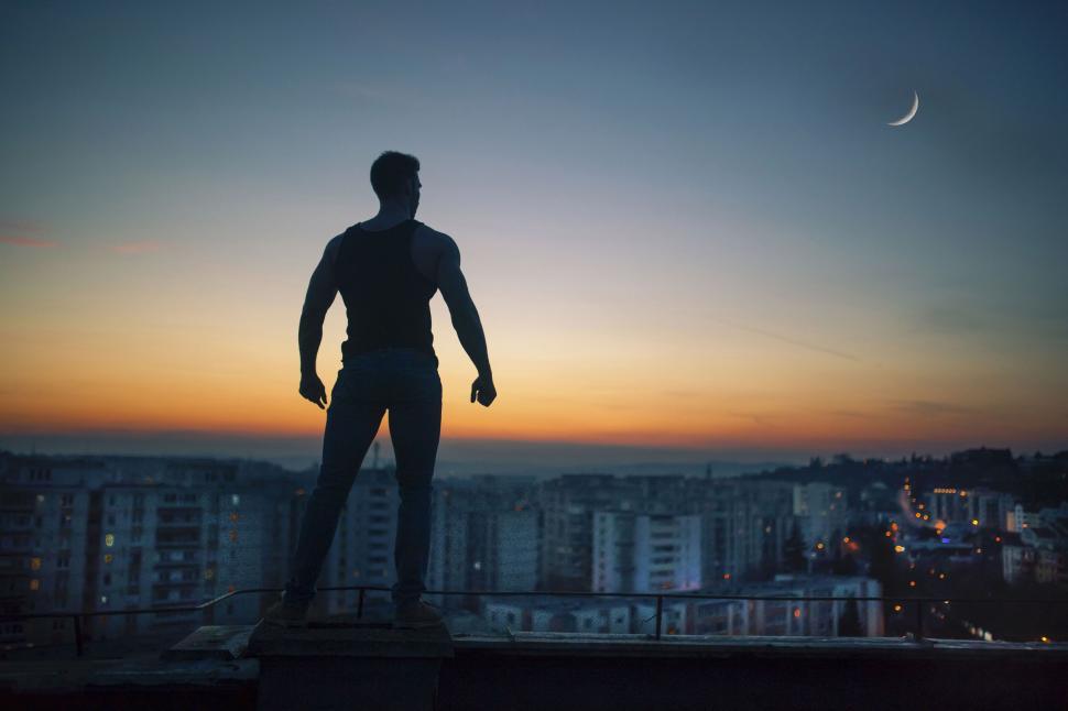 Free Image of Silhouette of man on rooftop at dusk 