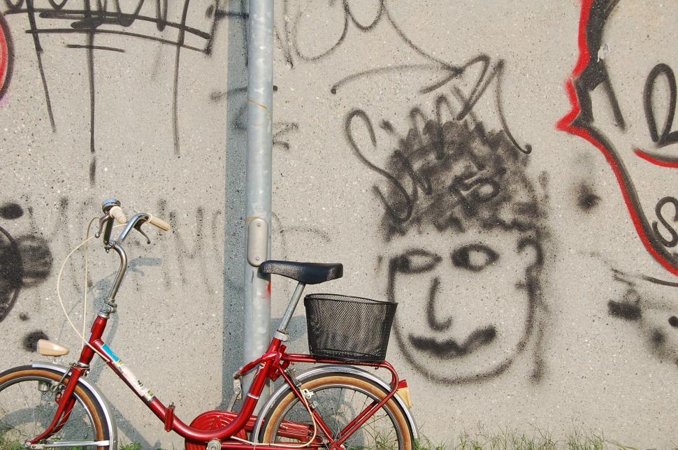 Free Image of Vintage red bicycle against tagged wall 