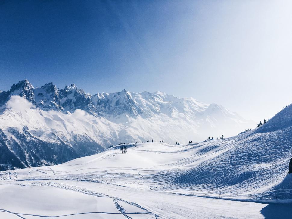 Free Image of Snow-covered ski slopes with mountain backdrop 