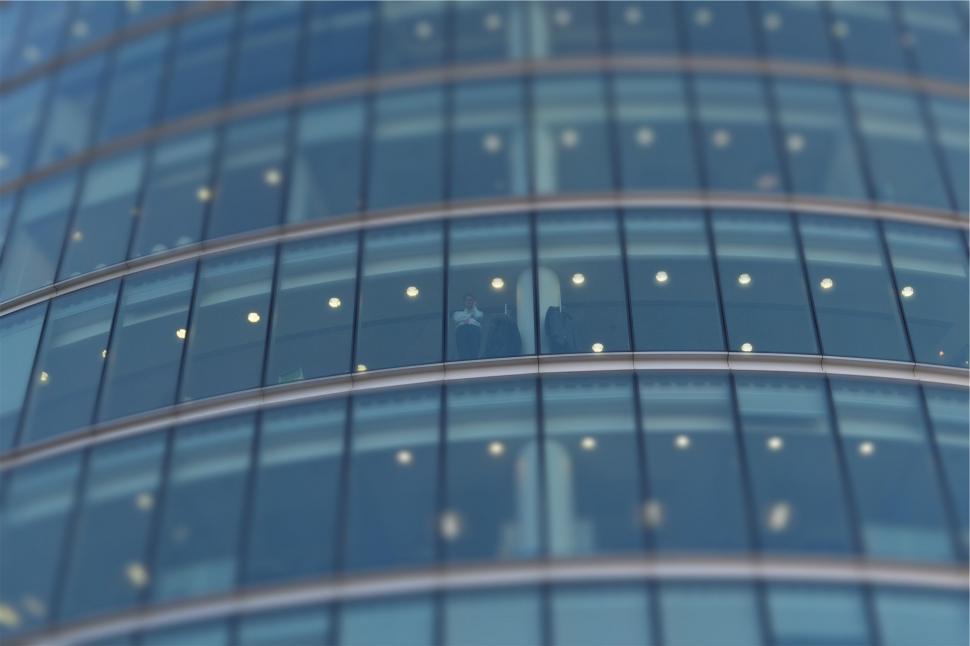 Free Image of Abstract reflection of people in a curved glass building 