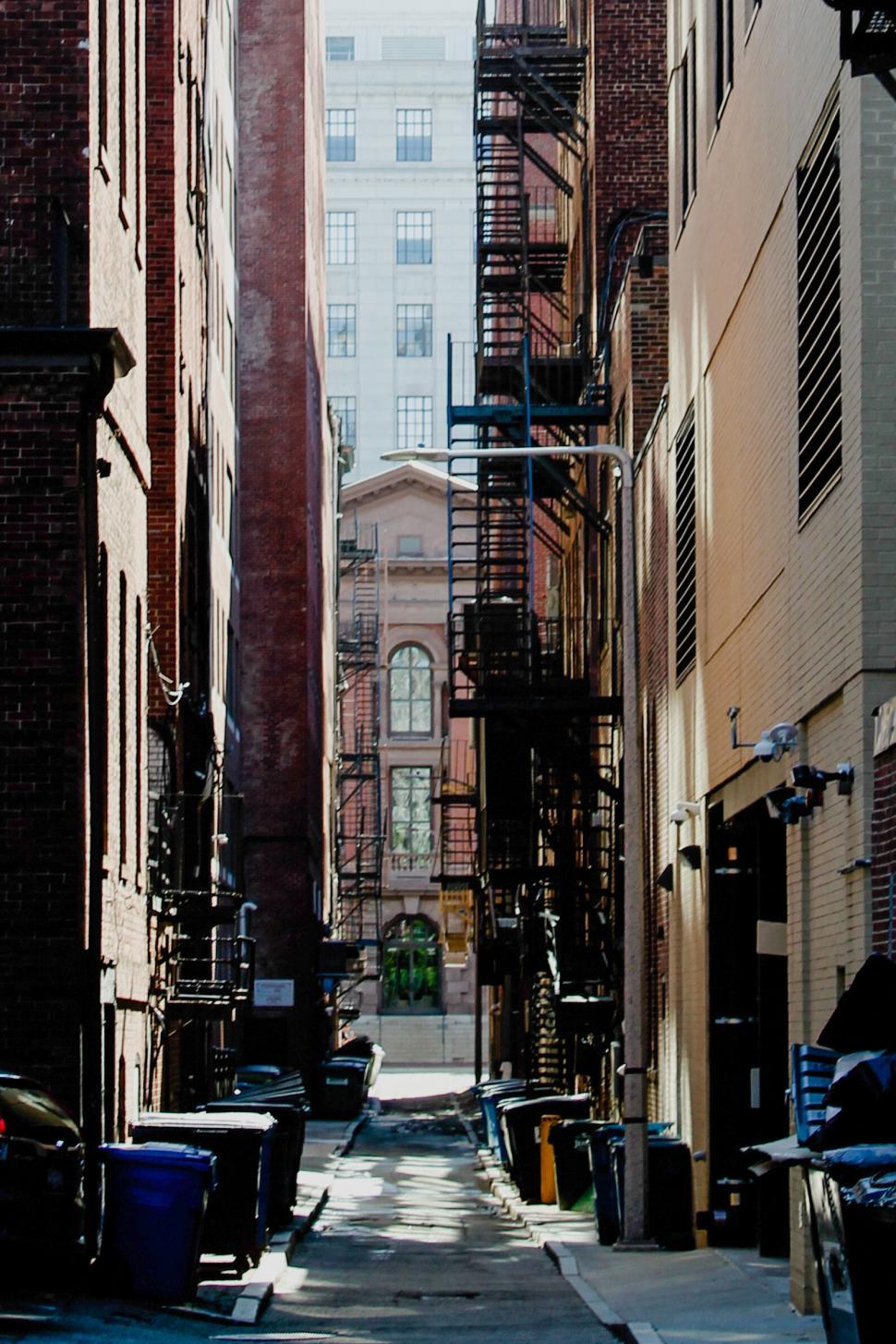 Free Image of Narrow urban alley with fire escape stairs in sunlight 