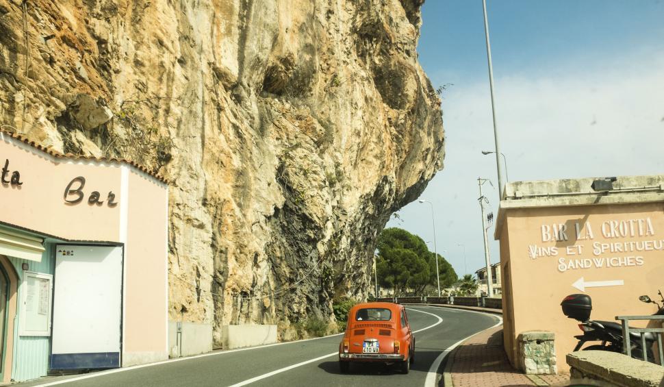 Free Image of Vintage car approaching rock-cut road 