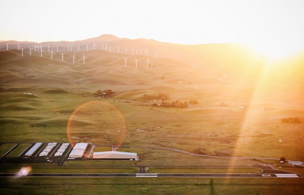 Free Image of Sunset over rolling hills with wind turbines 