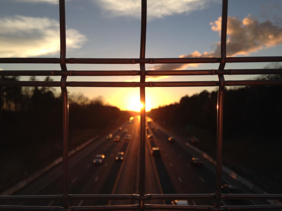 Free Image of Sunset view through a fence over highway 