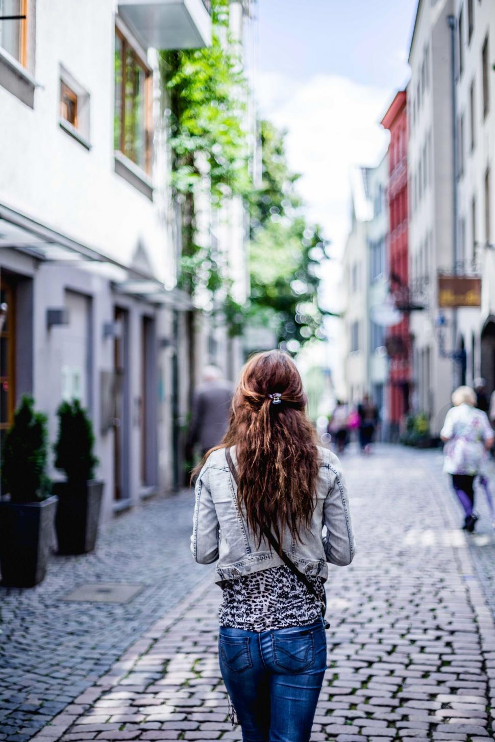 Free Image of Woman walking down a charming alleyway 