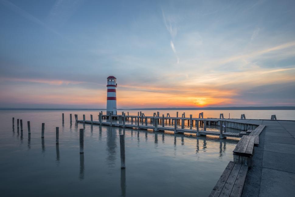 Free Image of Lighthouse at sunset by the calm lake 